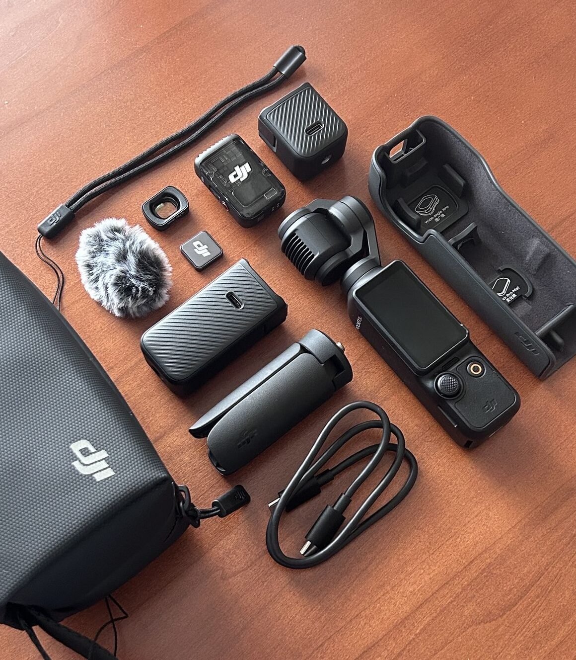 Bộ DJI Pocket cùng phụ kiện đi kèm bày trên mặt bàn gỗ
