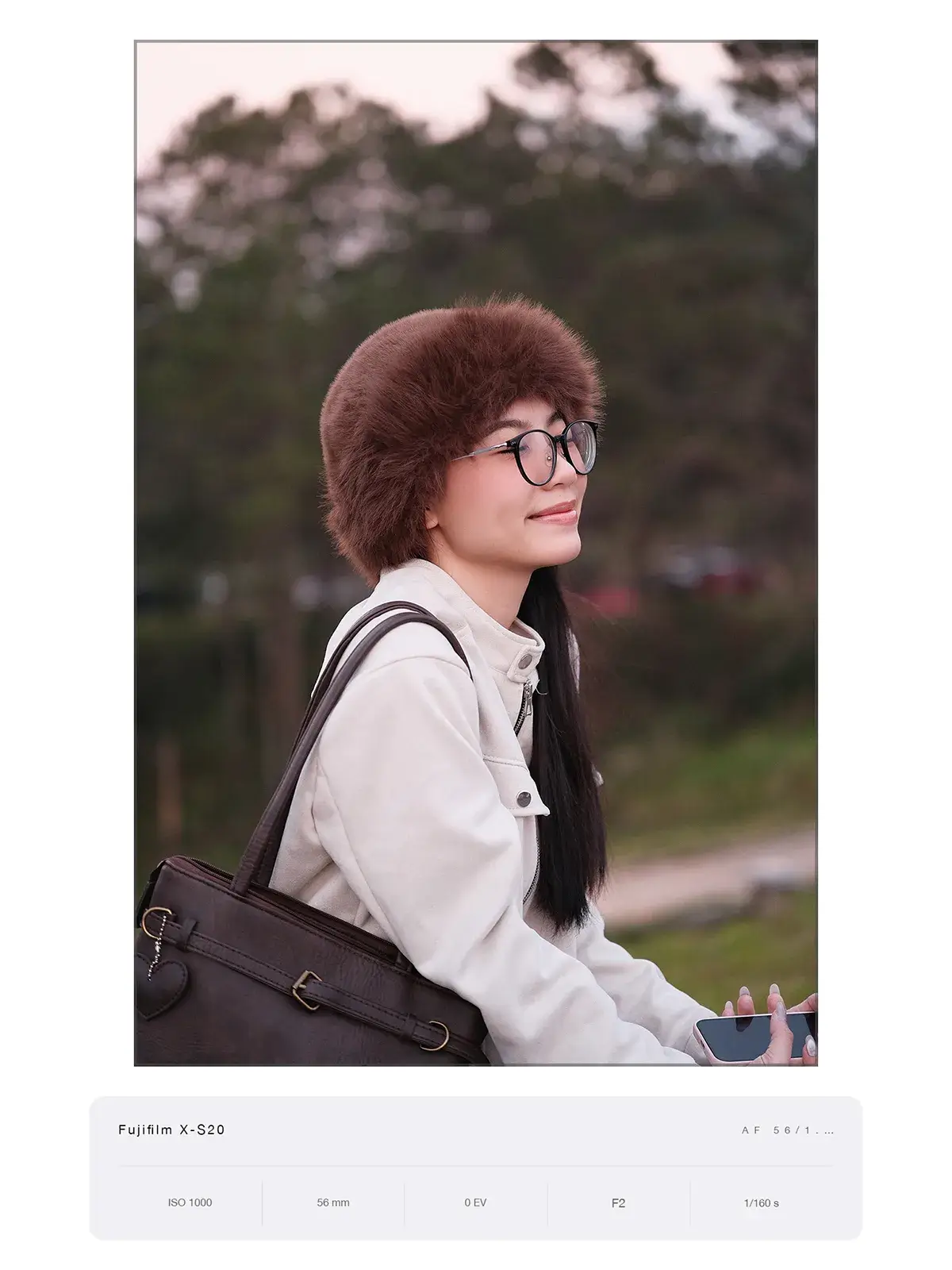 Chân dung nghiêng, cô gái đội mũ lông và đeo kính, hậu cảnh đồi thông xoá phông, chụp bằng Fujifilm X-S20