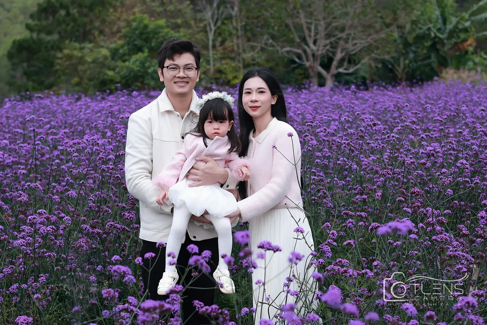 Gia đình ba người đứng giữa vườn hoa tím