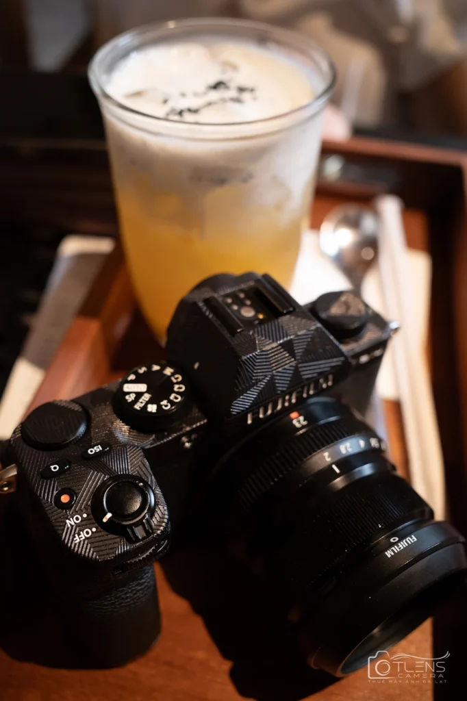 Bộ Fujifilm X-S10 gắn XF23mm F2 đặt cạnh đồ uống trên bàn