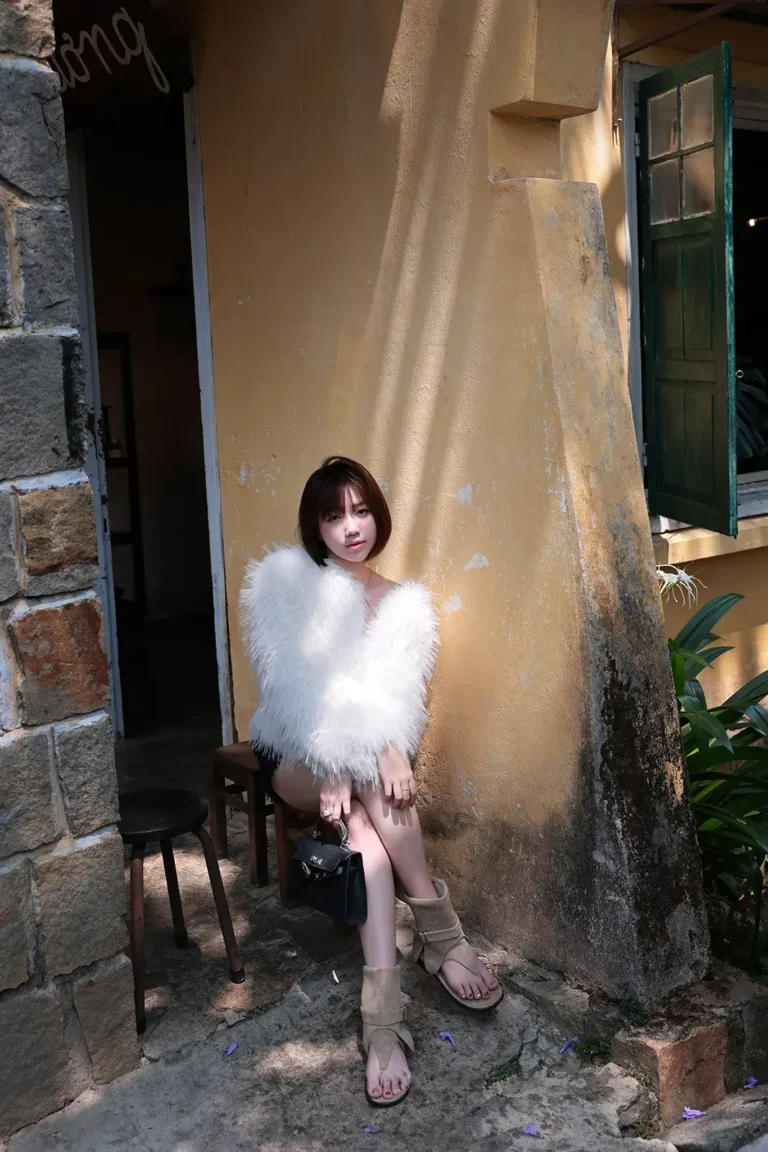 Ảnh outfit với áo khoác lông trắng bên tường vàng và cửa chớp xanh