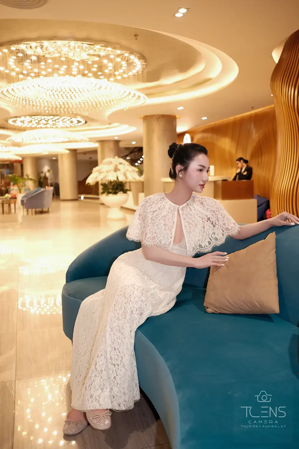 Ảnh chân dung một phụ nữ mặc váy ren trắng ngồi trên ghế xanh, chụp bằng Fujifilm X-S10 và XF23mm F2