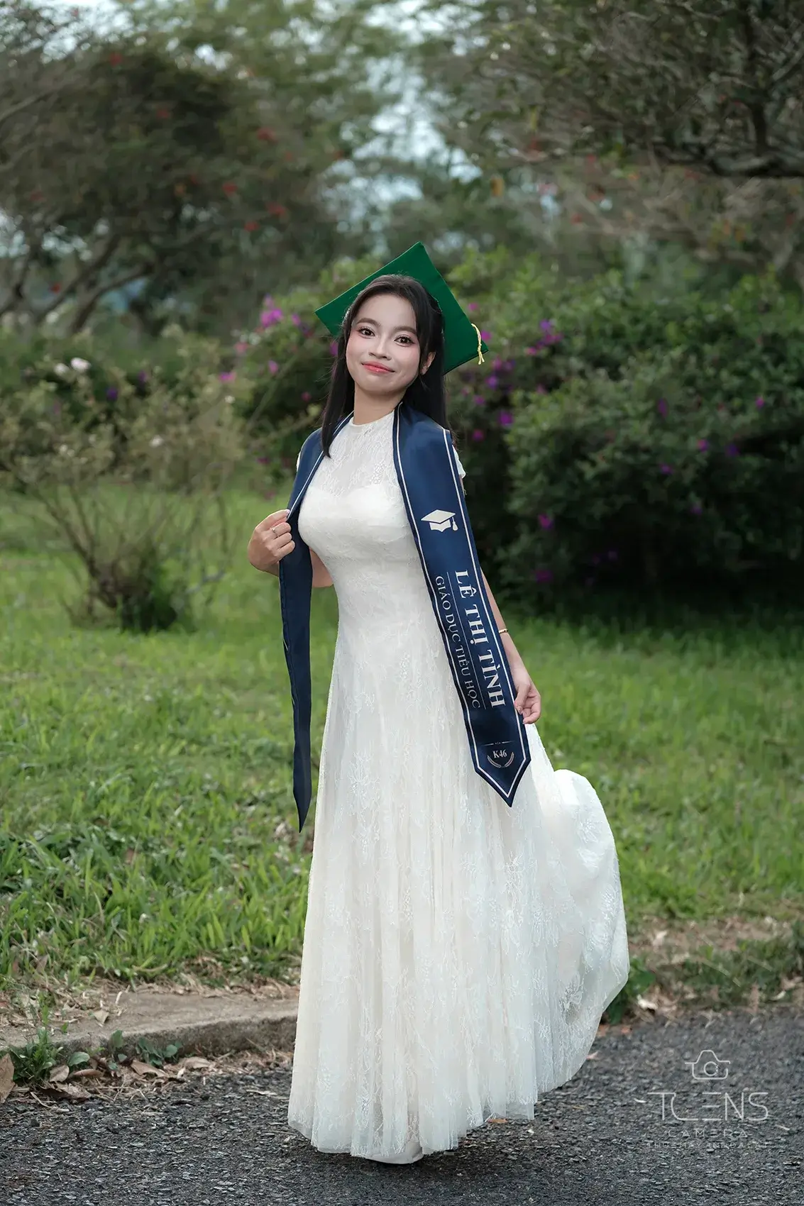 Một phụ nữ mặc váy trắng và khăn chấm bi đứng giữa cây xanh, chụp bằng Fujifilm X-T30 với Viltrox 56mm F1.7